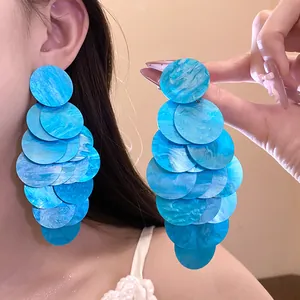 Detail of blue acrylic marbled disc earrings shown worn and held for scale and texture.