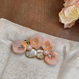Detailed close-up of French niche floral earrings with pink resin petals and pearls