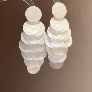 Close-up of elegant white marbled acrylic circular tassel earrings with a pearly finish.