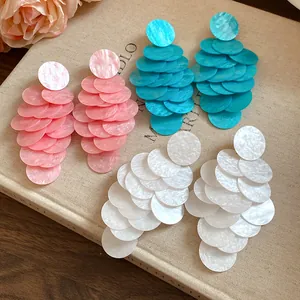 Close-up of bohemian acrylic round fringe earrings in pink, blue, and white colors