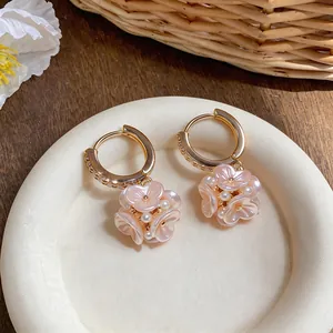 Dettaglio degli orecchini a cerchio con fiori rosa in stile francese e perle eleganti