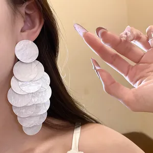 Detailed close-up view of elegant white acrylic layered circle drop earrings worn