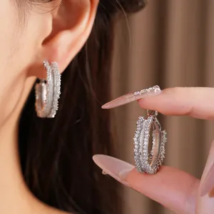Detailed view of sparkling zirconia encrusted wide silver hoop earrings on model