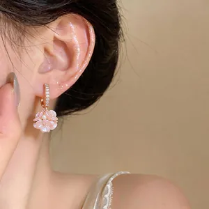 Dettaglio di un elegante orecchino a fiore rosa con piccole perle e accenti di zirconi