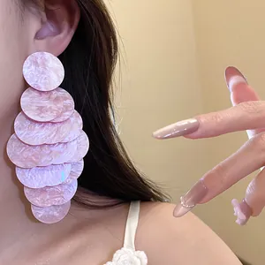 Close-up detail of pink marbled acrylic scale earrings showing layered disk texture