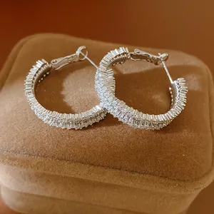 Detailed view of sparkling cubic zirconia inlaid silver hoop earrings on a brown velvet box