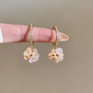 Dettaglio ravvicinato di orecchini a cerchio dorati con fiori rosa e perle eleganti
