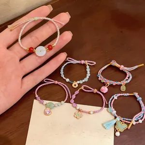 Macro view of hand-woven colorful rope bracelets featuring pearl and floral charms.