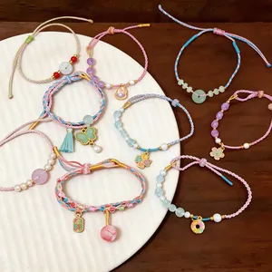 Close-up detail of handmade woven colorful rope bracelets with pearls and floral charms