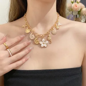Collier chaîne vintage doré avec breloques en émail coquillage et fleur blanche sur modèle