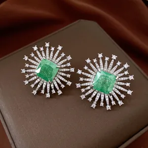 Primo piano di orecchini a fiore in zircone verde smeraldo con pietre bianche brillanti.