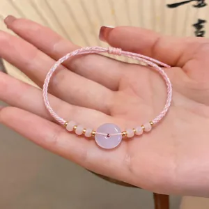 Close-up of handmade pink woven bracelet with lavender peace buckle bead detail