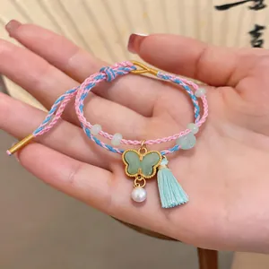 Detailed view of handmade braided bracelet with jade-like butterfly pendant and pearl