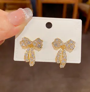 Primo piano di eleganti orecchini a lobo a fiocco scintillanti con micro-pavé di zirconi