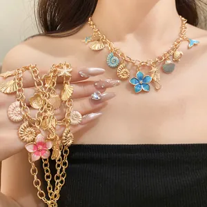 Vue détaillée d'un collier en chaîne dorée avec des breloques en émail en forme de fleurs.
