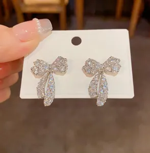 Dettaglio di orecchini a fiocco con zirconi scintillanti su un cartoncino bianco