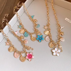 Détail de colliers vintage en émail avec pendentifs coquillages et fleurs colorées.