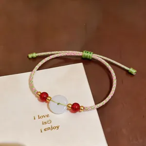 Detailed view of handmade pink and green woven cord bracelet with white jade donut bead