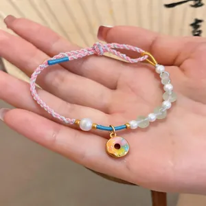 Hand-woven colorful cord bracelet with pearls and a cute rainbow donut charm in detail.