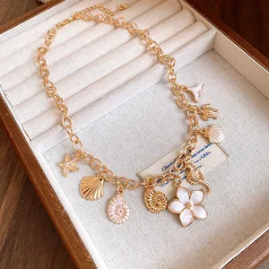 Gros plan d'un collier doré avec breloques coquillages, fleurs et animaux marins