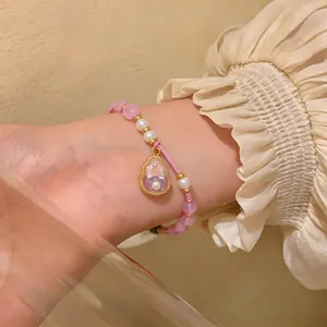 Detailed macro view of handmade braided bracelet with pink beads and pearl hulu charm.