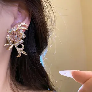 Elegant 18k gold plated flower earrings with pink zircons and pearls on a model ear.