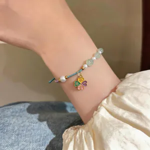 Close-up of a handcrafted woven bracelet with pearls and a four-leaf clover lucky charm