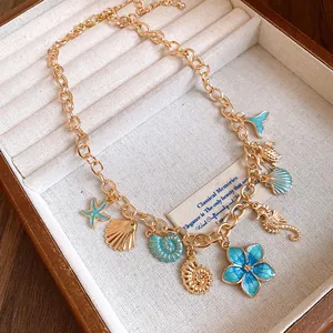 Détail du collier doré orné de breloques en émail bleu sarcelle (coquillages et fleurs)