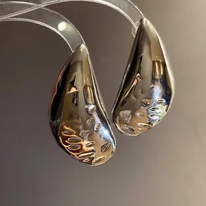 Minimalist silver teardrop stud earrings with textured metal finish for high-end fashion