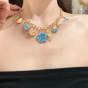 Détail d'un collier doré vintage avec des breloques de coquillages et fleurs en émail.