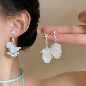 Gros plan de boucles d'oreilles étoile de mer avec glands de pétales de fleurs en coquille