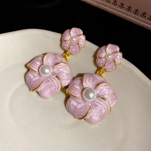 Detailed close-up view of pink enamel floral earrings featuring pearls and gold trim