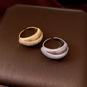 Dettaglio di anelli aperti placcati oro 14k con texture a coste e micro pavé di zirconi