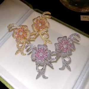 Detailed view of elegant pink zircon flower earrings with pearl in gold and silver finishes.