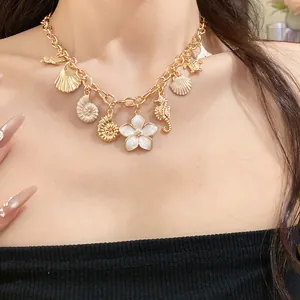 Vue détaillée d'un collier doré avec pendentifs coquillages et fleurs sur le cou.