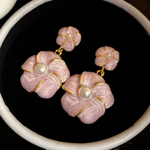 Macro view of French retro pink floral earrings with central pearl detail