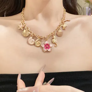 Vue détaillée du collier océanique doré avec des pendentifs fleur rose et coquillages