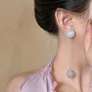 Elegant long drop earring featuring a luminous pearl stud and a sparkling pavé sphere.