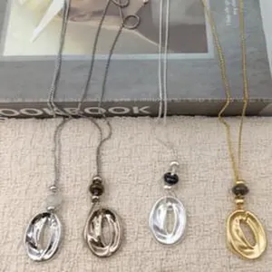 Four long necklaces featuring organic wrinkled circular pendants in metallic finishes