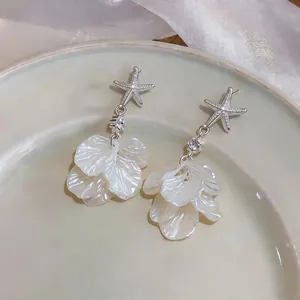 Vue détaillée de boucles d'oreilles étoile de mer avec pétales de fleurs en nacre