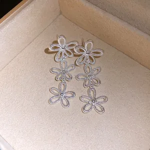 Detailansicht der silbernen, hohlen dreifachen Blumen-Ohrringe in einer Samt-Schmuckschatulle