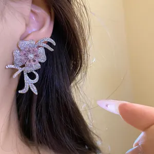 Close-up of elegant 18k gold plated flower earring with sparkling zircons and a central pearl