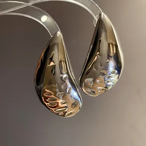 Detailed view of minimalist silver water drop earrings with a textured metallic finish