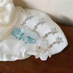 Vue détaillée de boucles d'oreilles étoile de mer avec pétales en nacre sur soie.