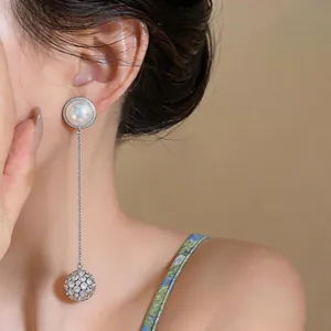 Detailed view of elegant silver drop earring with pearl and sparkling rhinestone ball
