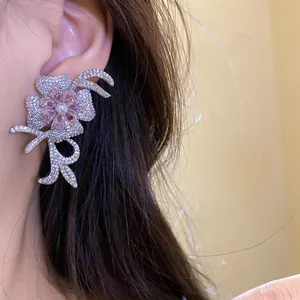 Macro detail of elegant 18k gold plated flower stud earring with pink zircons and pearl