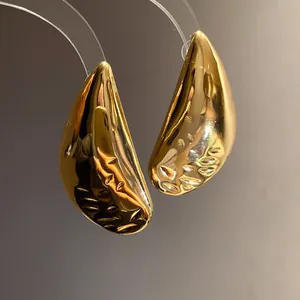 Macro view of textured gold water drop stud earrings with a high-shine metallic finish.