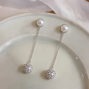 Close-up detail of French style earrings with elegant round pearls and crystal ball pendants.