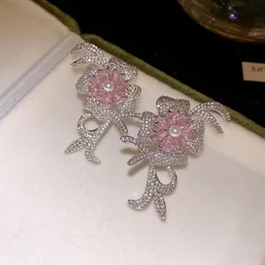 Macro view of elegant flower stud earrings with pink zirconia petals and white pearl centers.