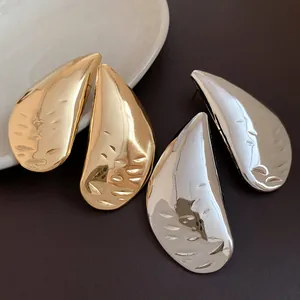 Detailed view of textured gold and silver water drop earrings with premium metallic finish
